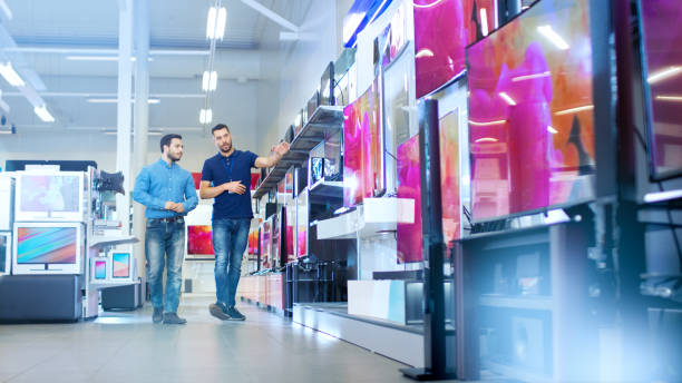 istock In the Electronics Store Professional Consultant Shows Latest 4K UHD TV's to a Young Man, They Talk about Specifications and What Model is Best for Young Man's Home. Store is Bright, Modern and Has all the Latest Models. 853324218