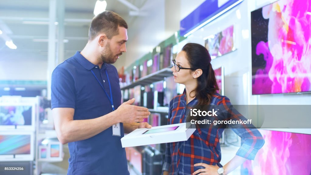 In der Elektronik-Shop bietet professionelle Berater Beratung auf Tablet Computerspezifikationen für schöne junge Frau. Laden ist hell, Modern und hat die neuesten Geräte. - Lizenzfrei Geschäft Stock-Foto