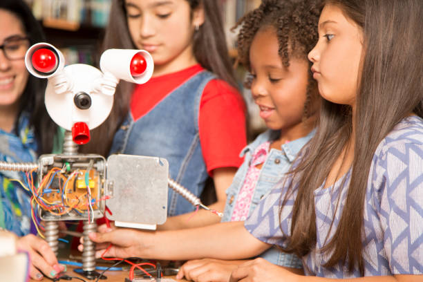 istock Elementary age school girls, teacher build robot in technology class. 853325190