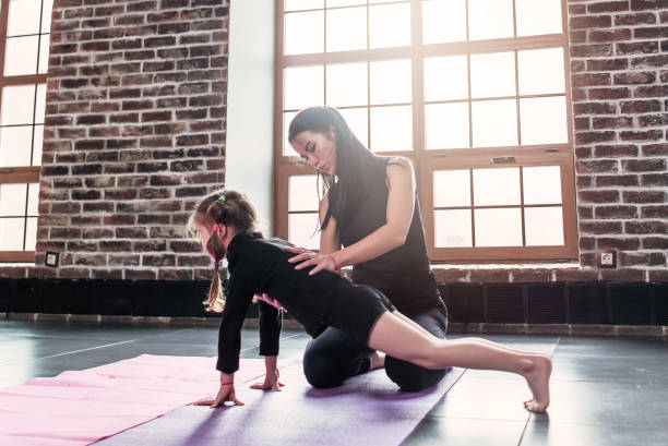 junge trainer helfen kleine mädchen plank trainieren im sportverein - yoga good posture women little girls stock-fotos und bilder