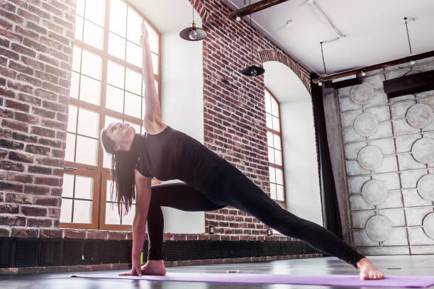 istock Young sporty woman practicing yoga doing triangle pose, trikonasana, on mat 853329672