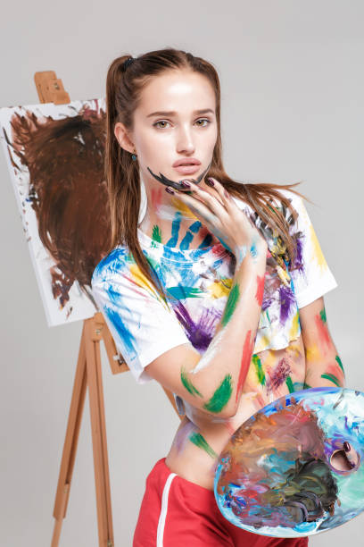 istock woman painter soiled in colorful paint draws on canvas. 853329970