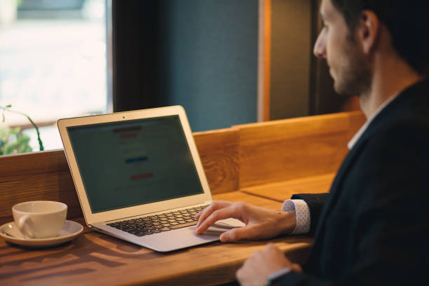 Arm typing on a laptop with cup of coffee