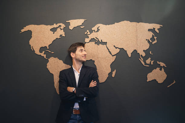 istock Young man looking to world map with crossed hands 853336430