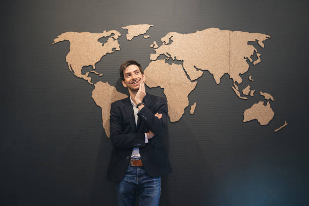 istock Young man looking to world map with crossed hands 853336500