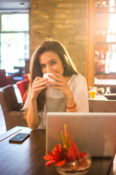 istock Young woman holding coffee cup and smiling in a cafe. 853351670