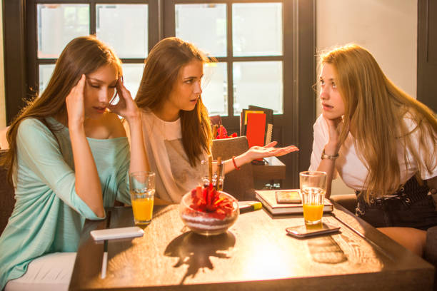Angry, irritated teenage girlfriends arguing in cafe.