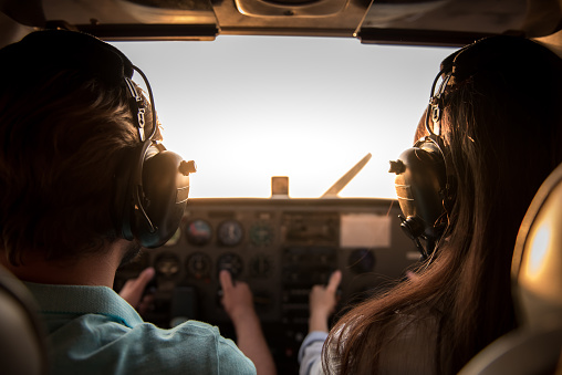 Back view from the inside of the plane, couple in aviation headsets is ready to fly