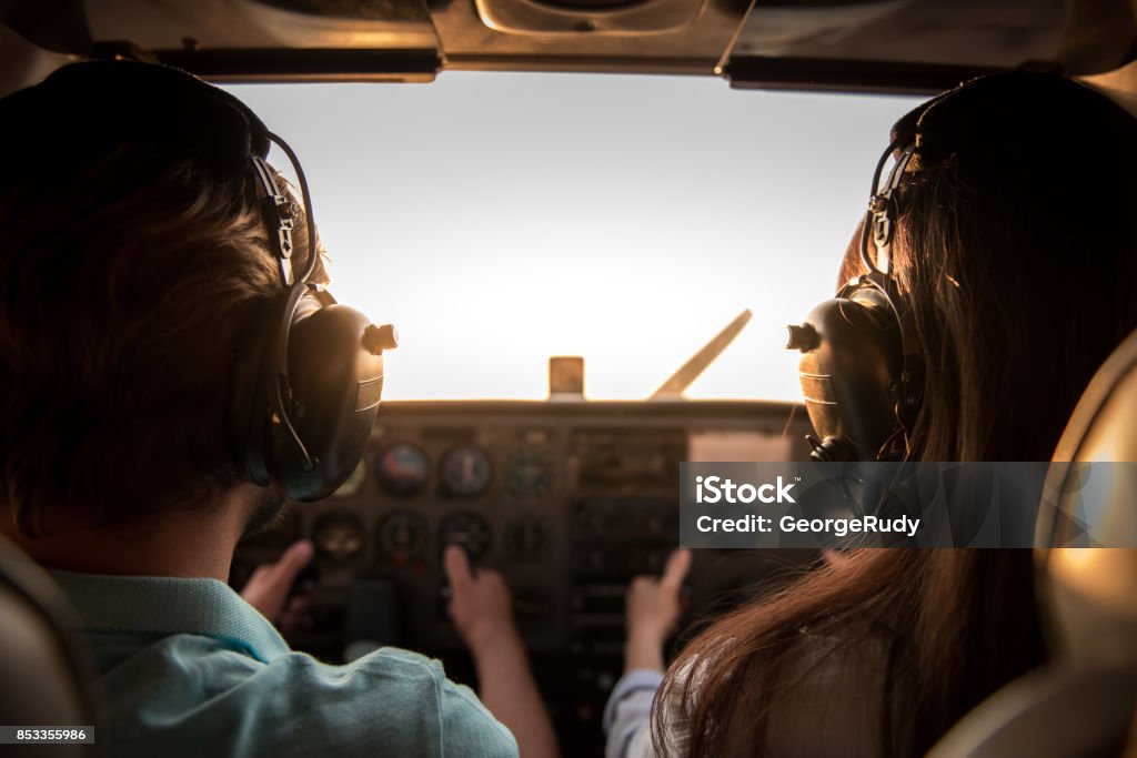 Couple in aircraft Back view from the inside of the plane, couple in aviation headsets is ready to fly Instructor Stock Photo