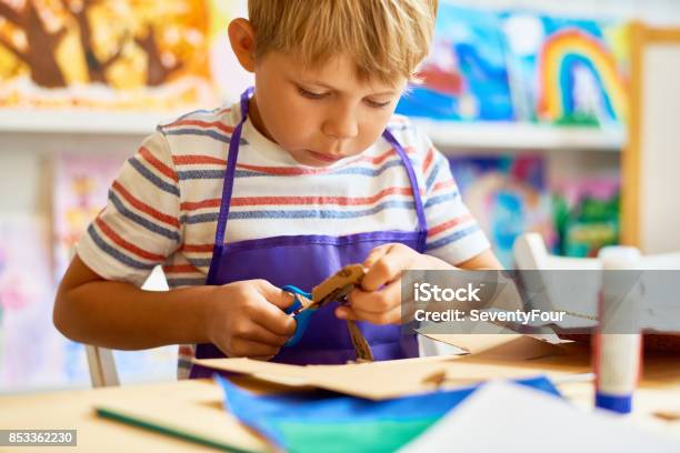 Little Boy Cutting Paper In Craft Class Stock Photo - Download Image Now - Child, Craft, Cardboard