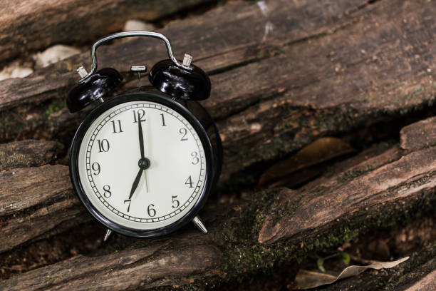 Vintage style old clock on wood background time at 7 o'clock morning