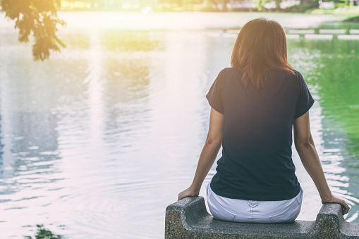 teen sitting alone feeling lonely and thinking missing someone looking out at water lake