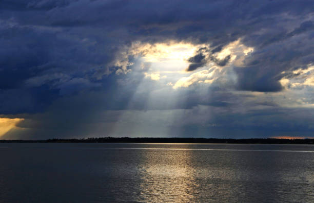 istock dark storm clouds circle of light shining down on bay water 853381492