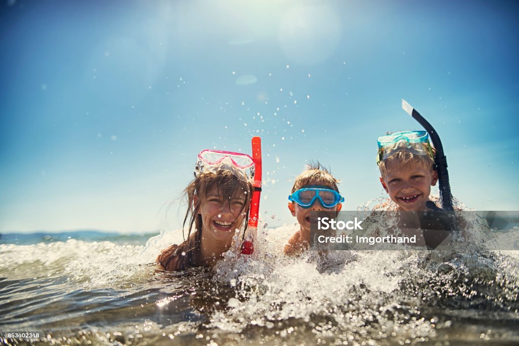 Kids having fun snorkeling in beautiful sea Little boys and their elder sister having fun snorkeling in beautiful sea. The boys aged 8 and girl aged 11 are laughing in warm clear water, wearing diving goggles and snorkel. Sunny summer day.
 Snorkeling Stock Photo