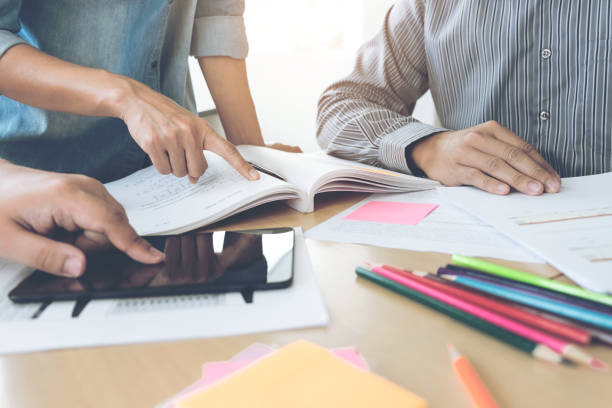 istock Education, teaching, learning, technology and people concept. Group of high school students or classmates with helps friend catching up workbook learning in classroom, Tutor books with friends 853406454