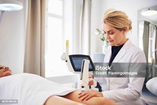 Clinic Technician Performing Laser Hair Removal On A Clients Leg Stock Photo - Download Image Now