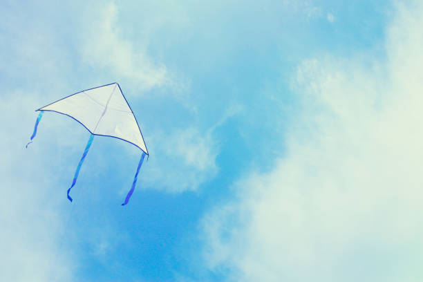 Colorful kite shaped like an eagle flying in the blue sky through the clouds