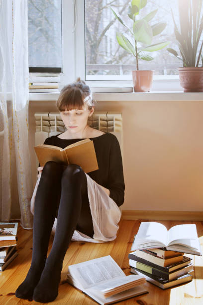 istock Young woman sitting on a floor and reading a book 853442984