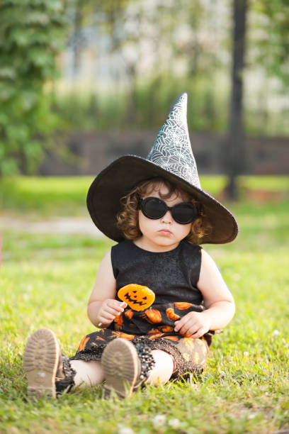 istock Little girl witch in black pointed hat and sunglasses. 853447048