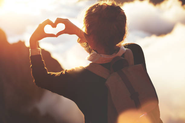 istock Woman making heart shape with hands high in mountains 853461164