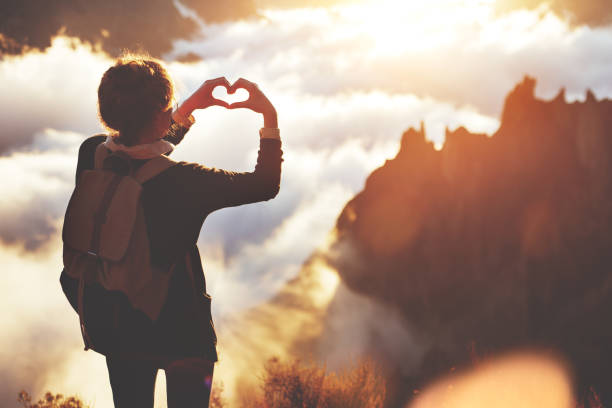 istock Woman making heart shape with hands high in mountains 853461384