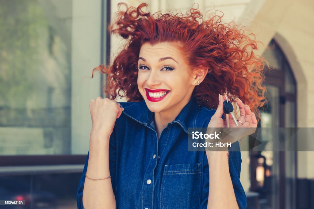 Portrait closeup beautiful smile latina graduate graduated student girl young woman in cap gown showing thumbs up holding diploma scroll isolated green background wall. Celebrating graduation ceremony Just won an apartment!!! Super excited Smiling red head curly girl holding showing keys to her new home isolated near apartment complex outdoors. Business woman real estate agent renting agent concept Car Stock Photo