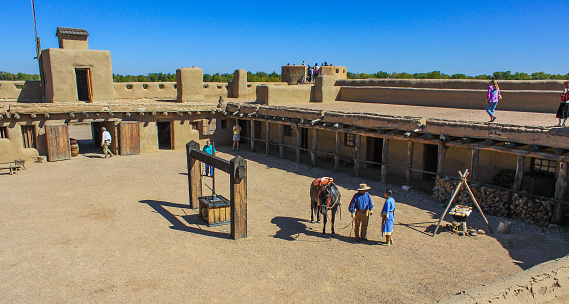 Employees in period costumes and visitors amble around the Old West era Fort, Bent's Old Fort National Historic Site.
