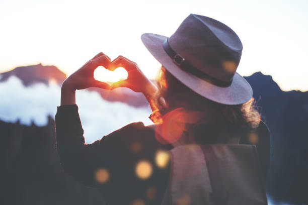 istock Woman making heart shape with hands high in mountains 853467902