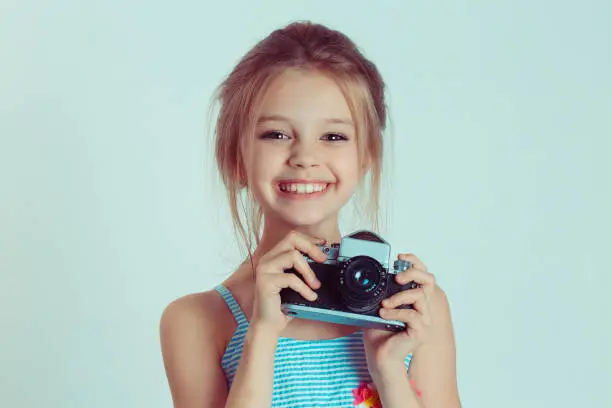 Beautiful smiling happy child (kid, girl) holding taking pictures looking at you camera gesture