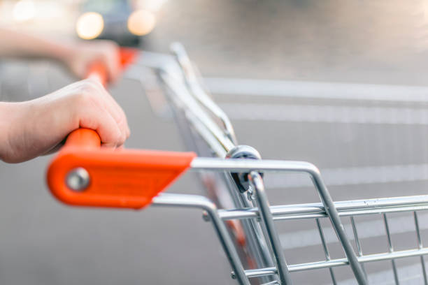 primo piano della donna con carrello della spesa. donna spingendo carrello della spesa al supermercato. giovane donna che fa shopping al supermercato. l'acquirente spinge un carrello al supermercato - store opening foto e immagini stock