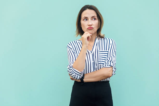 istock Thoughtful business woman looking away while standing against light blue wall. 853503358