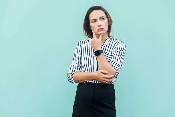 istock Thoughtful business woman looking away while standing against light blue wall. 853503410