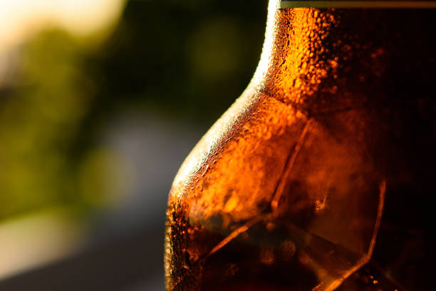 Refreshing Brown Cold Beer Bottle Covered With Condensation A close-up shot of refreshing a brown cold beer bottle covered with condensation. sunset dew stock pictures, royalty-free photos & images