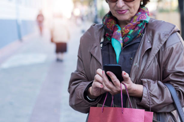 istock Senior woman using a mobile on a city street 853517646