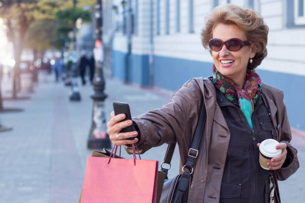 istock Senior woman using a mobile on a city street 853517798