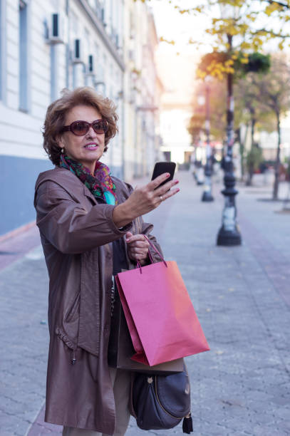 istock Senior woman using a mobile on a city street 853518230