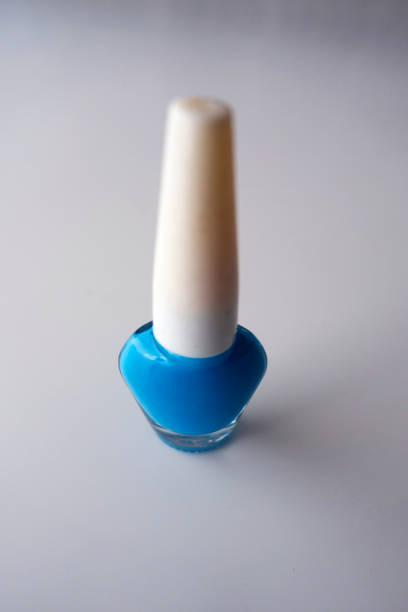 A bottle of blue nail polish on a black background