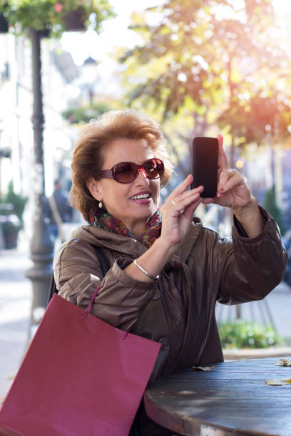 istock Senior woman using a mobile on a city street 853522436