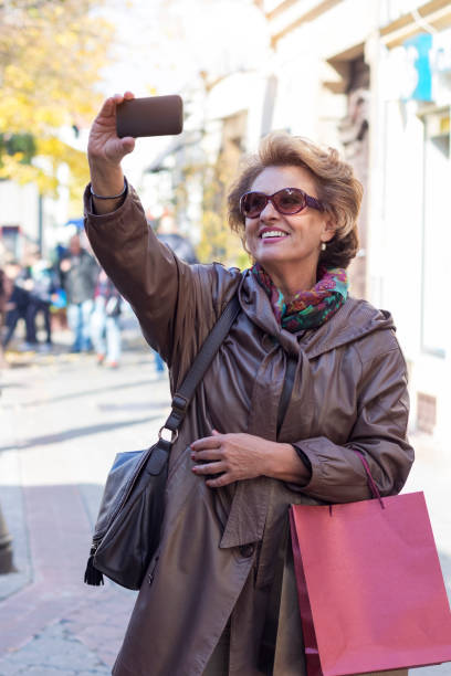 istock Senior woman using a mobile on a city street 853522446