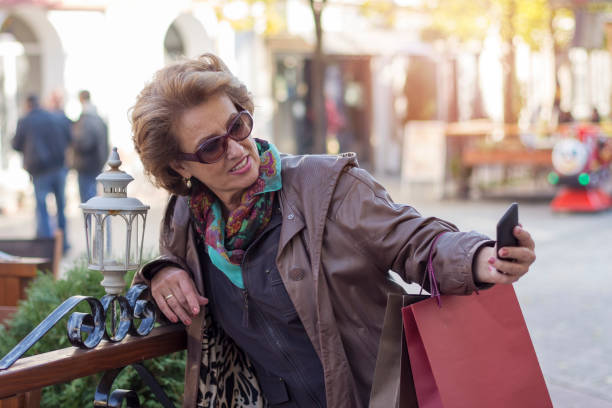 istock Senior woman using a mobile on a city street 853522480