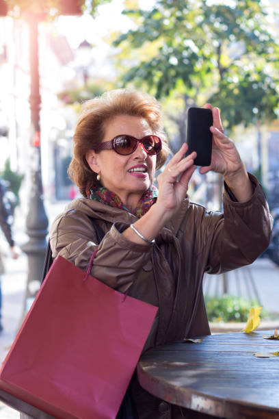 istock Senior woman using a mobile on a city street 853522846