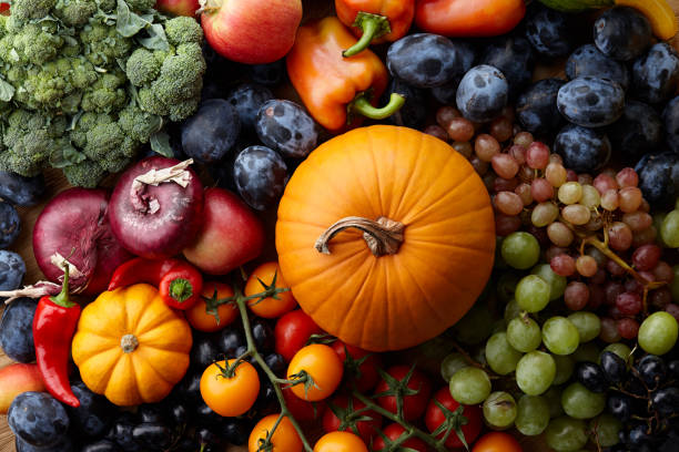 Autumn concept with seasonal fruits and vegetables Autumn harvest concept. Seasonal fruits and vegetables on a wooden table, top view abundance stock pictures, royalty-free photos & images