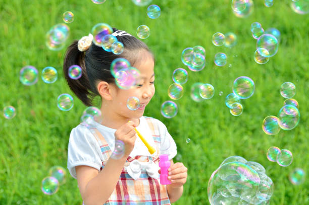 istock Girls playing with soap bubbles in the grassland 853528986