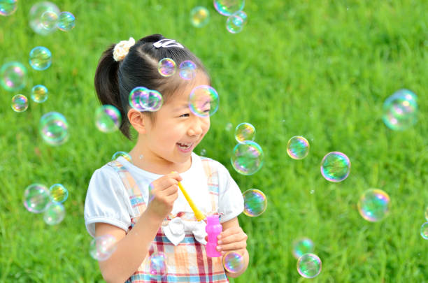 istock Girls playing with soap bubbles in the grassland 853528996