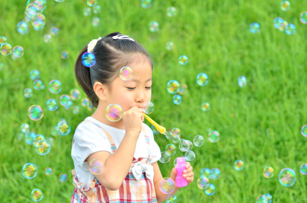 istock Girls playing with soap bubbles in the grassland 853529000