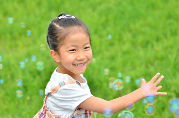 istock Girls playing with soap bubbles in the grassland 853529020