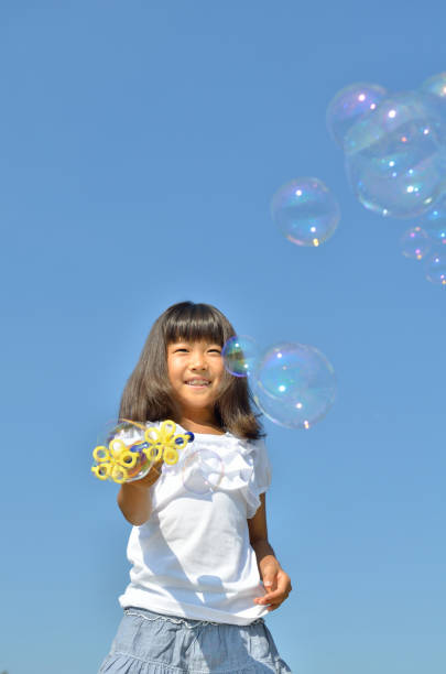istock Girls playing with soap bubbles in the blue sky 853529056