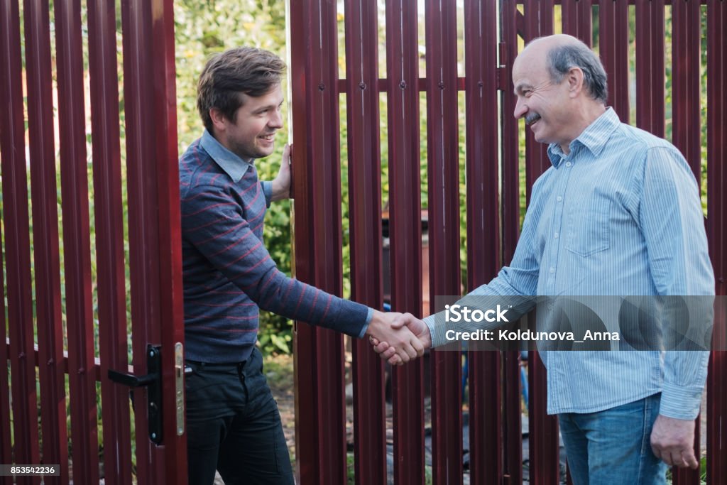 two farmers shaking hands and takling to each other two farmers shaking hands and takling to each other on sunny day Neighbor Stock Photo