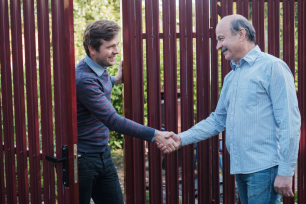 two farmers shaking hands and takling to each other two farmers shaking hands and takling to each other on sunny day neighbour stock pictures, royalty-free photos & images