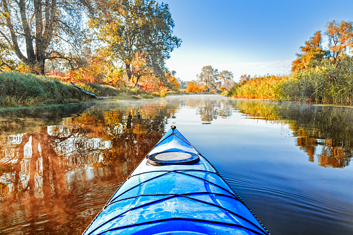 istock View from the blue kayak on the river banks with autumnal yellow leaves trees in fall season. The Seversky Donets river, autumn kayaking. View over nose of bright blue kayak. 853546746